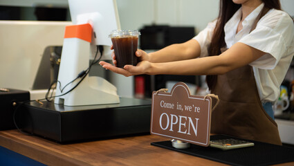 Coffee Business Concept Beautiful lady smiling at camera offers disposable take away ice coffee at the coffee shop