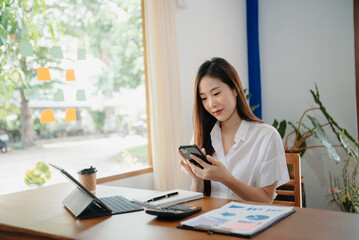 Young attractive Asian female office worker business suits smiling on desk in home office