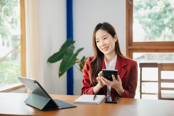 Young attractive Asian female office worker business suits smiling on desk in home office