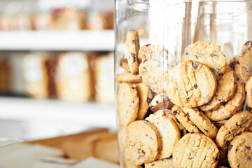 Dessert, bakery and closeup of jar with cookies for coffee shop, sugar and junk food. Cooking, chocolate and nutrition with oatmeal biscuit in container in cafe for snack, breakfast and pastry