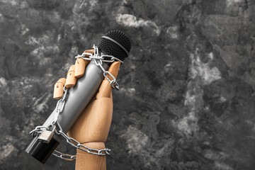 Wooden hand with microphone and chains on dark background, closeup. Censorship concept