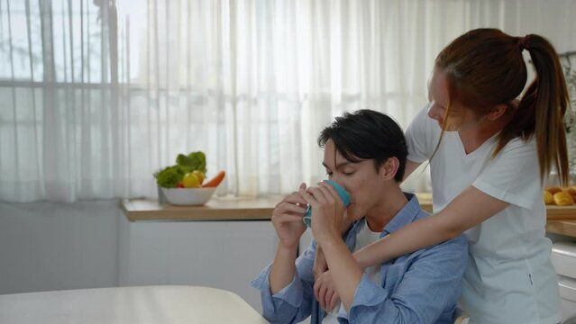 Asian couple having morning drink in the kitchen, family relationship concept, love, care
