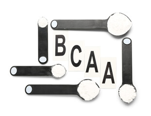 Letters BCAA and scoops of amino acid supplement on white background