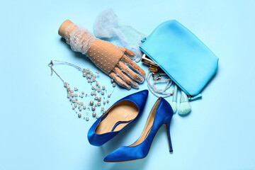 Composition with stylish heels, accessories, cosmetics and wooden hand on color background