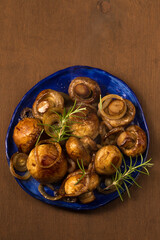 Fried mushrooms champignons with rosemary and onions on a plate