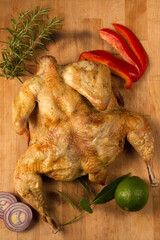 Baked tobacco chicken with spices on a wooden background