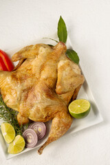 Baked tobacco chicken with spices on a plate on a white background