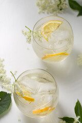 A delicious summer drink made of elderflowers and lemon with ice on a light background