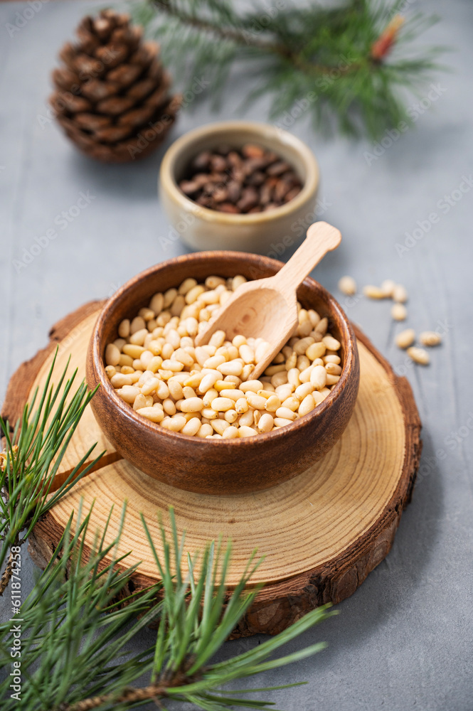 Wall mural pine nuts in a bowl on a wooden board on a blue texture background with branches of pine needles and