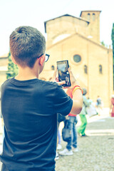 Boy enjoying the  view  of Saint Stephen church at  Bologna . Concept of traveling famous landmarks in Italy. Caucasian  Boy tourist   making a photo with a phone 