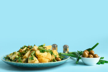 Plate of tasty Potato Salad with vegetables on blue background