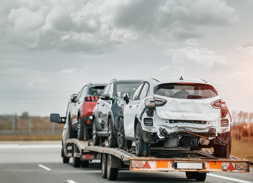 Roadside Assistance on the Highway After a Traffic Accident. side view of the fltabed tow truck with a damaged vehicles after a traffic accident.