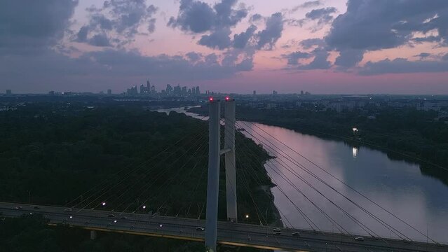 Beautiful panoramic aerial drone view to cable-stayed Siekierkowski Bridge over the Vistula river and Warsaw City skyscrapers, Poland in June dusk hour evening.