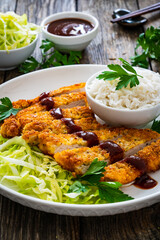Tonkatsu - crispy Japanese pork chop with white rice and fresh vegetables on wooden table
