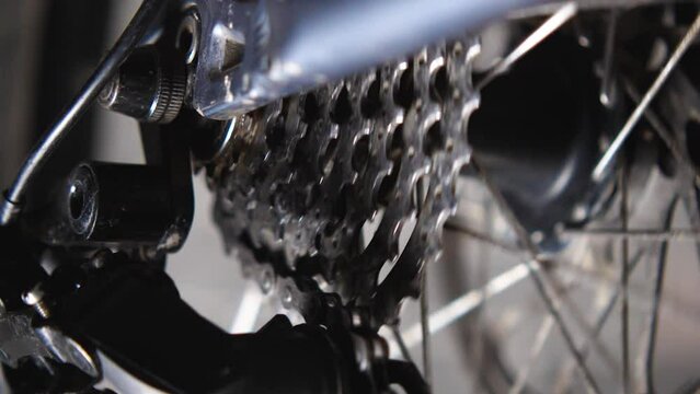 Close-up of a rotating bicycle wheel and cassette. Checking the operation of the transmission after repairs. Bicycle repair and maintenance workshop. Slow motion