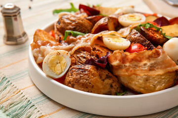 Plate of tasty potato salad with eggs, tomatoes and bacon on table, closeup