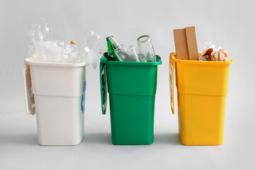 Containers with different types of garbage on light background. Recycling concept
