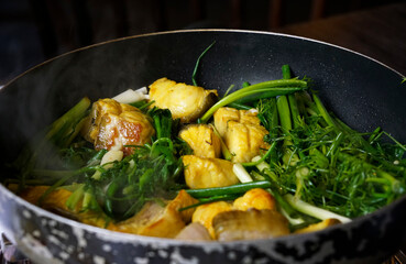 Delicious turmeric fish served on pot with fresh greenery