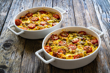 Bread casserole with mozzarella cheese, tomatoes and scrambled eggs on wooden table