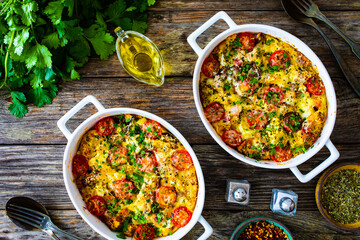 Bread casserole with mozzarella cheese, tomatoes and scrambled eggs on wooden table