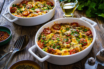 Bread casserole with mozzarella cheese, tomatoes and scrambled eggs on wooden table