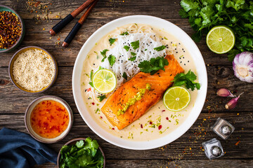 Creamy coconut lime salmon with rice noodles on wooden table