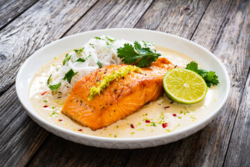 Creamy coconut lime salmon with rice noodles on wooden table