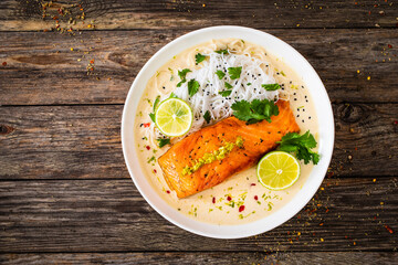 Creamy coconut lime salmon with rice noodles on wooden table