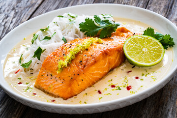 Creamy coconut lime salmon with rice noodles on wooden table