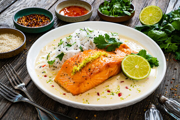 Creamy coconut lime salmon with rice noodles on wooden table