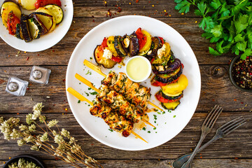 Greek chicken souvlaki with Greek style roasted vegetable casserole on wooden background