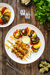 Greek chicken souvlaki with Greek style roasted vegetable casserole on wooden background