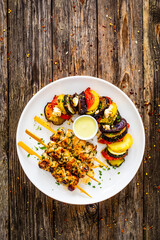 Greek chicken souvlaki with Greek style roasted vegetable casserole on wooden background