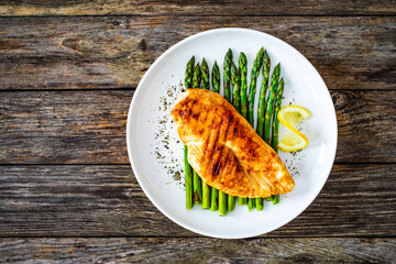 Grilled chicken breast and green asparagus on wooden table