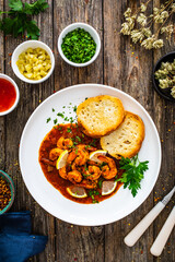 Louisiana style shrimp in hot sauce with bread on wooden table