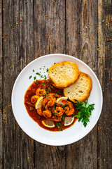 Louisiana style shrimp in hot sauce with bread on wooden table
