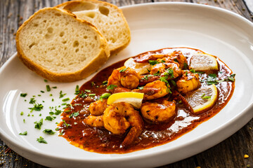 Louisiana style shrimp in hot sauce with bread on wooden table
