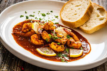 Louisiana style shrimp in hot sauce with bread on wooden table