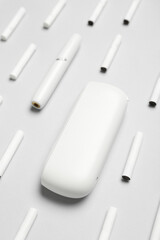 Modern electronic cigar and many sticks on grey background