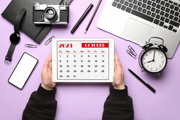 Fototapeta na wymiar Woman holding tablet computer with calendar near different gadgets on lilac background