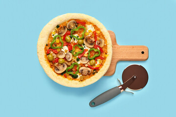 Board with vegetable pizza and cutter on blue background