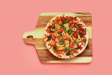 Wooden board with vegetable pizza on pink background