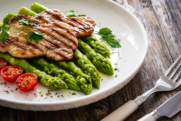 Grilled meat and asparagus on wooden table
