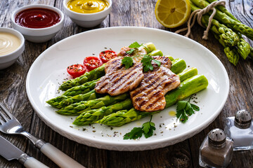Grilled meat and asparagus on wooden table
