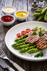 Grilled meat and asparagus on wooden table

