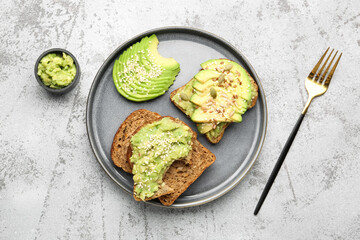 Plate of tasty avocado toasts on light background