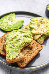 Plate of tasty avocado toasts on light background, closeup