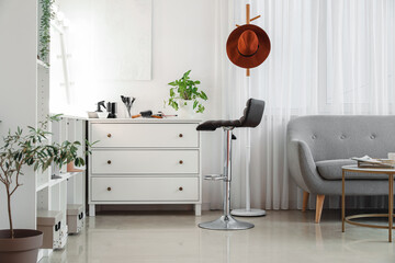 Stylish chest of drawers with hairdressing tools and chair in beauty salon