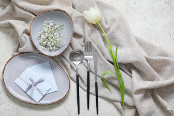 Fototapeta na wymiar Composition with blank invitation card, cutlery, plates and tulip flowers on white table