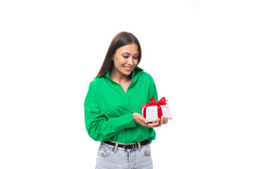 cute young brown-eyed brown-haired woman with makeup in a green blouse decides to prepare a gift for her boyfriend's holiday